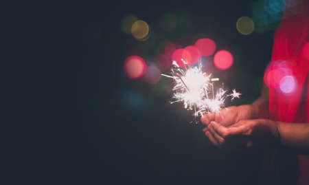 Festive sparkler with sparks in hands, New Year's celebration sparkler at night,copy space for text.の写真素材