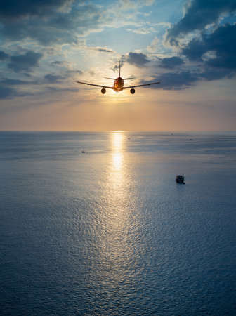 Airplane flying over tropical sea atduring sunset,copy space for text.