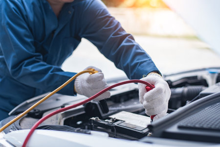Battery charging. Terminals and hands. auto repair a gas station, hand up close using jumper wires to electrically charge a car battery.の写真素材