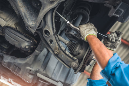 man changes a wheel hub with a wheel bearing in a car, Car disk brake pad replacement service by hand of mechanic man in car garageの写真素材