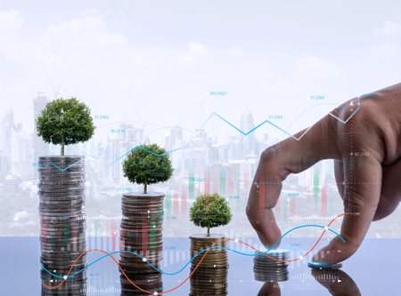 A businessman holding a coin with a growing tree on it and a tree growing on a stack of cash. maximizing return on investment for a company.の写真素材