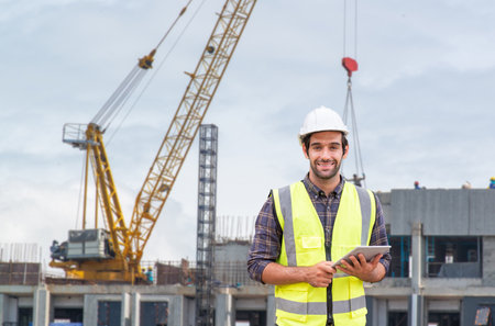 Business, building, industry, technology, and people concept - jovial builder in hardhat over group...