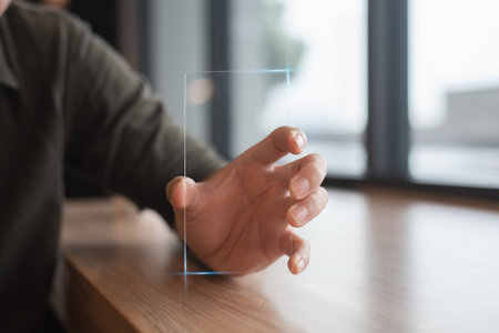 Close-up of a man's hand clutching and displaying a transparent smartphone at work for the business, technology, and people theme.の写真素材