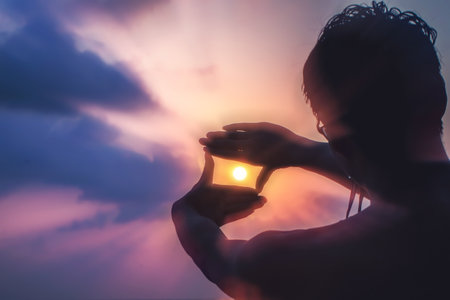 Young man drawing a frame around the sun with his hands at sunrise. Concept for futureÂ planning idea.の写真素材