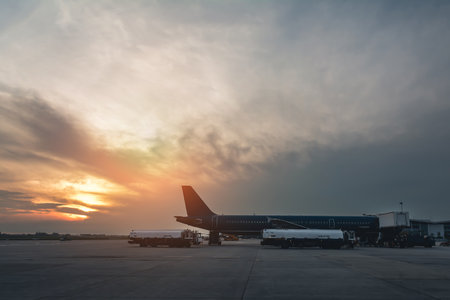 Modern international airport in the early morning with an airplane at the terminal gate preparing to...