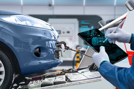 A mechanic uses a digital tablet to diagnose and inspect a blue car in a high-tech automotive repair shop.の写真素材