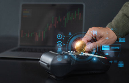 A hand holding a Bitcoin coin over a payment terminal, symbolizing cryptocurrency transactions, with...