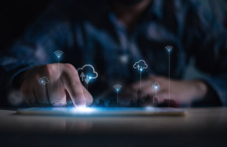 A person interacts with a digital tablet, displaying cloud computing, data storage, and wireless network icons, symbolizing modern technology and connectivity.の写真素材