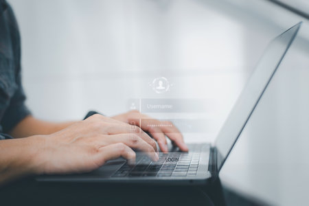 Close-up of hands typing on a laptop keyboard with a digital login screen overlay, symbolizing...