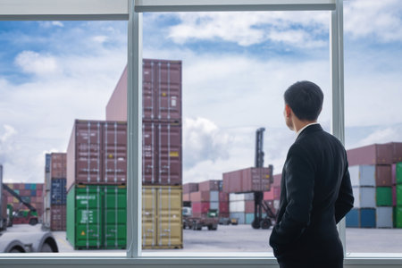 Rear view of businessman watching cargo containers at shipping port. Concept of global logistics, supply chain, and import-export business management.の写真素材