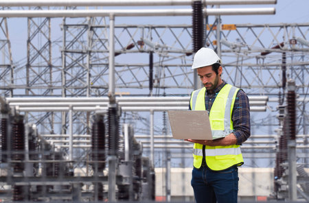 Professional engineer using a laptop with futuristic digital data overlays to inspect equipment at a high-voltage electrical power substation.の写真素材
