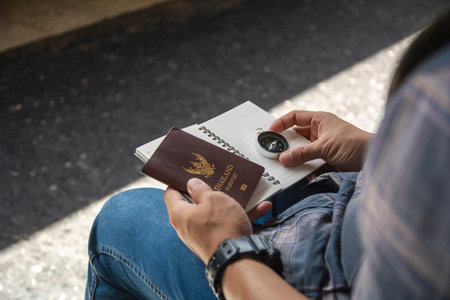 Traveler hands holding Thailand passport, compass, and notebook. Concept of journey planning, tourism, navigation, and exploring new destinations.の写真素材