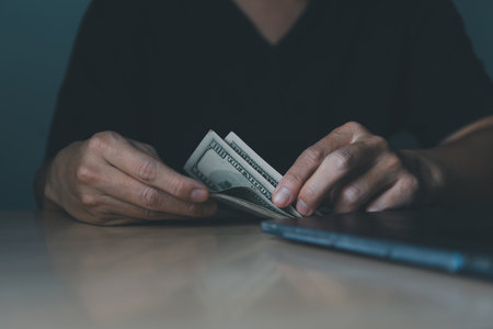 Close-up of man hands counting stack of US 100 dollar bills at the table. Concept of financial management, business profit, investment, and checking exchange rates.の写真素材