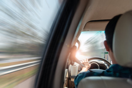 Rear view of man driving car on highway. View from back seat with fast motion blur background...
