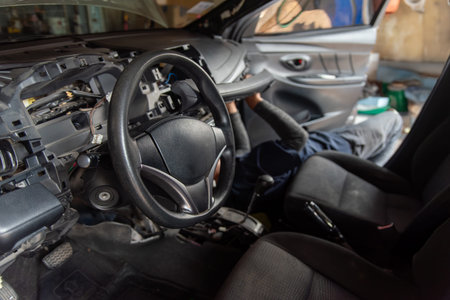 Professional auto mechanic working on car interior. Dashboard removed for air conditioner evaporator or heater core replacement in service garage.の写真素材