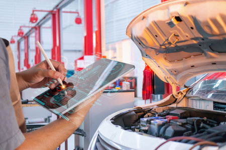 Automotive technician checking car engine using a digital tablet with a smart holographic diagnostic interface in a modern repair workshop.の写真素材