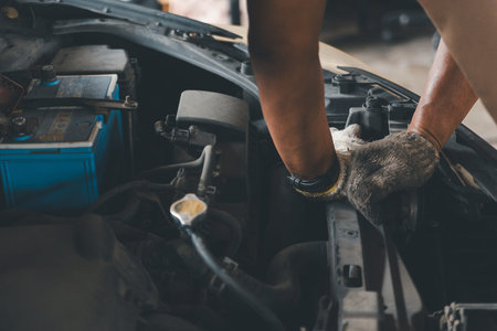 Close-up of auto mechanic hands checking and repairing car engine. Automotive maintenance service, routine check-up, and car breakdown concept.の写真素材