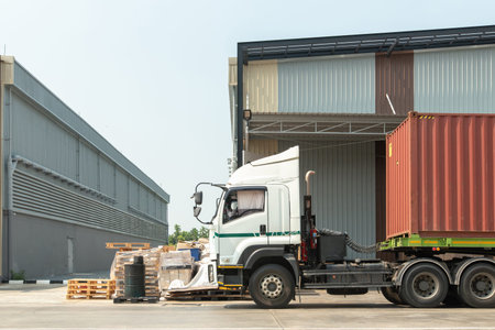 Side view of a heavy-duty truck with a shipping container at a distribution center. Concept of global logistics, freight transportation, and supply chain management.の写真素材