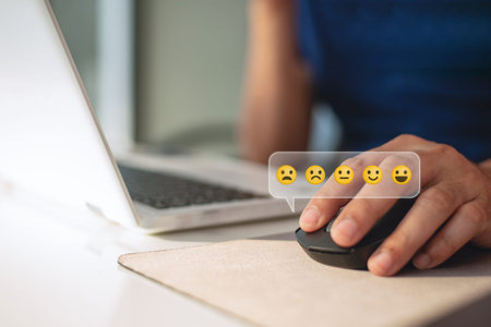 Close up of a person using a computer mouse to click a virtual emoji rating scale. Concept for customer satisfaction, online reviews, and user feedback surveys.の写真素材