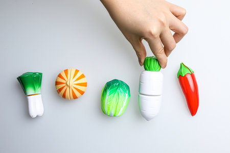 Woman's hand putting red and green hot chili peppers on a white backgroundの写真素材