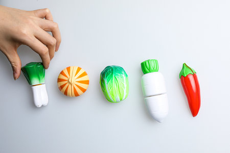 Female hand holding green, red, orange and yellow pepper on white backgroundの写真素材