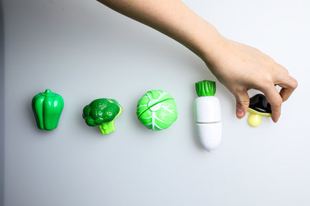 Woman's hand holding green and white plastic caps on white background.の写真素材