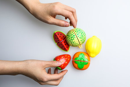 Children's hands play with plasticine and fruits on a white backgroundの写真素材