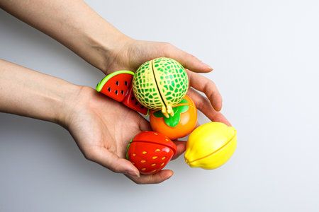 Woman's hands holding different toys on a white background, top view