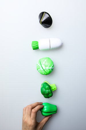Woman's hand holding a green capsule on a white background with copy spaceの写真素材