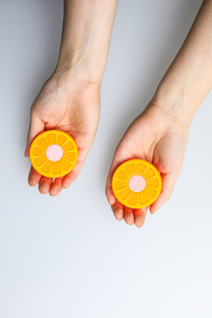 Female hands holding two halves of an orange on a white background.の写真素材