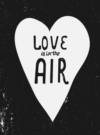Love is in the air hand drawn lettering design. Romantic postcard. Love card design. Phrase inside white heart on black textured backgroundのイラスト素材