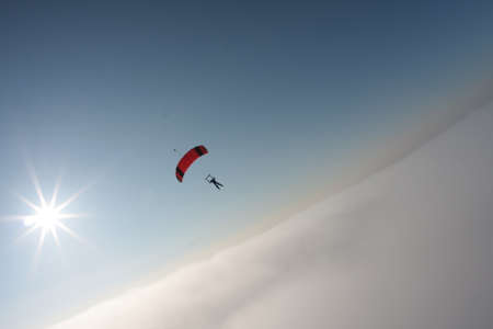 skydiver flying in the background of blue sky and sunの写真素材