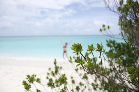 Blurred silhouette of the jumping girl on the white sandy beach on the Kuramathi Maldives island in the summer vacationの写真素材