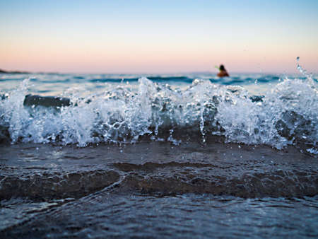 Close up of splashes of a wave crashing at a sandy tropical beach and the diver