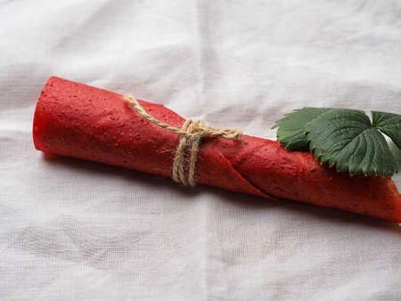 Red strawberry fruit leather rolls lie on the brown sackingの写真素材