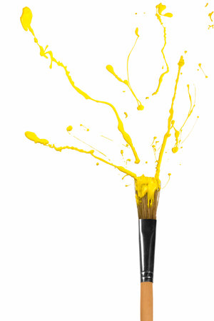 Yellow paint bursting out of wooden paintbrushの写真素材