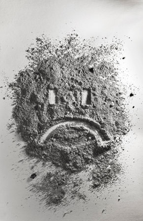 Sad emoticon made of grey ashの写真素材
