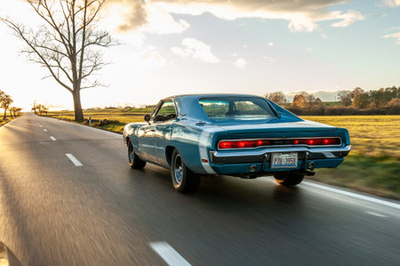 Classic american car on the road at sunset, motion blur. Dodge Charger 500 1970