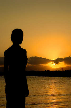 a young girl watching  the gold sunsetの写真素材