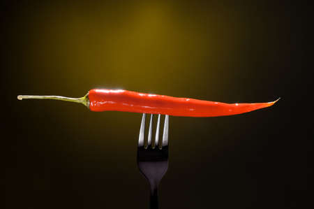 a red chili pepper on the forkの写真素材