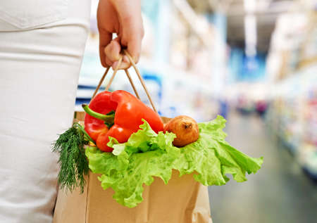 a woman holding a bag of fruitの写真素材