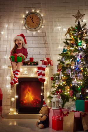 Smiling funny child in Santa red hat holding Christmas gift in hand.の写真素材