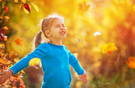 happy little child, baby girl laughing and playing in the autumn on the nature walk outdoorsの写真素材