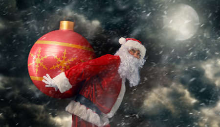 Portrait of Santa Claus with huge Christmas bauble.の写真素材