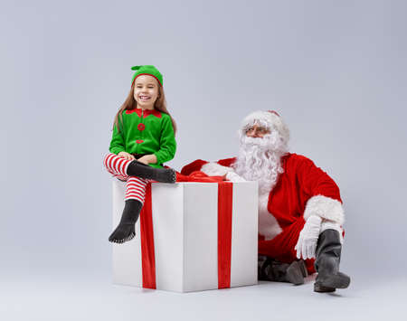 Jolly elf and Santa Claus play together.