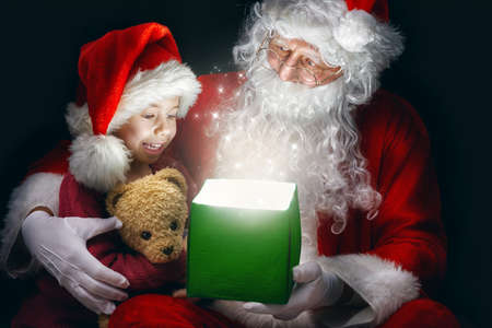 Cute little girl and Santa Claus opening a magic gift box.の写真素材