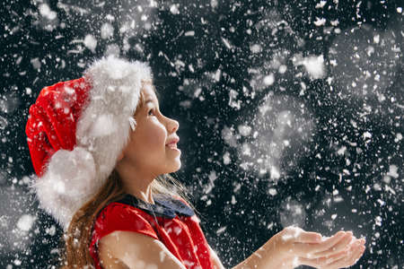 a Christmas miracle! happy little girl catching snowflakes in her handsの写真素材