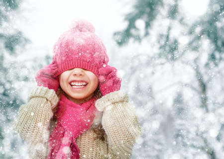 Happy child girl playing on a winter walk in nature