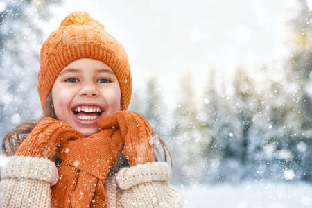 happy child girl plaing on a snowy winter walkの写真素材