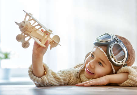 happy child girl playing with toy airplane. the dream of becoming a pilotの写真素材